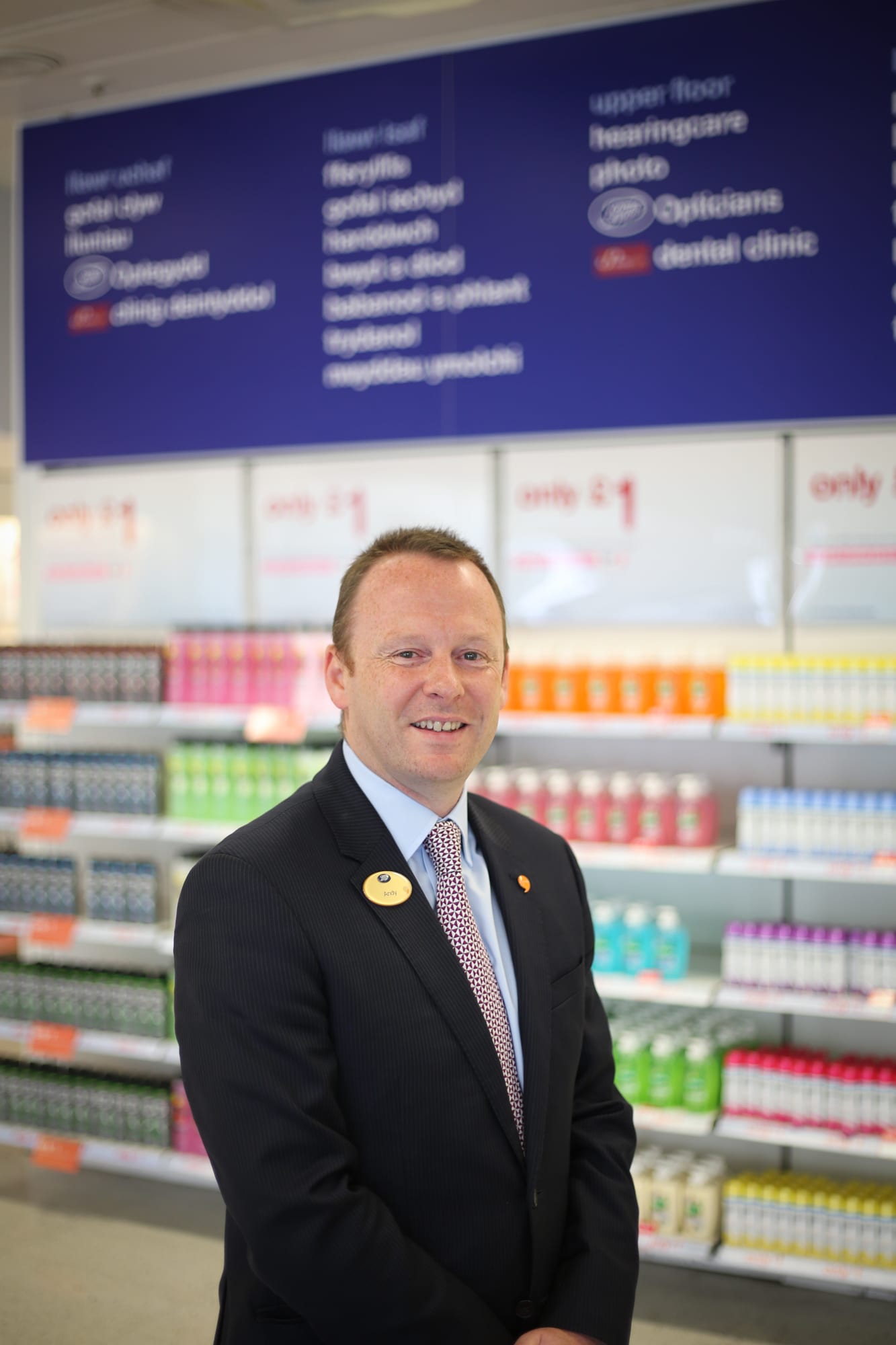 Andy Francis smiles in front of merchandise inside a Boots store.