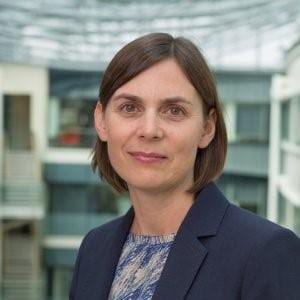 Claire Griffin in navy suit jacket looks into the camera