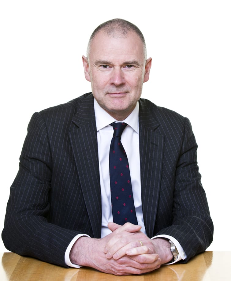 David Oldfield sits at a table with his hands clasped