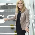 Jo Dow looks up at the camera, an office atrium behind her