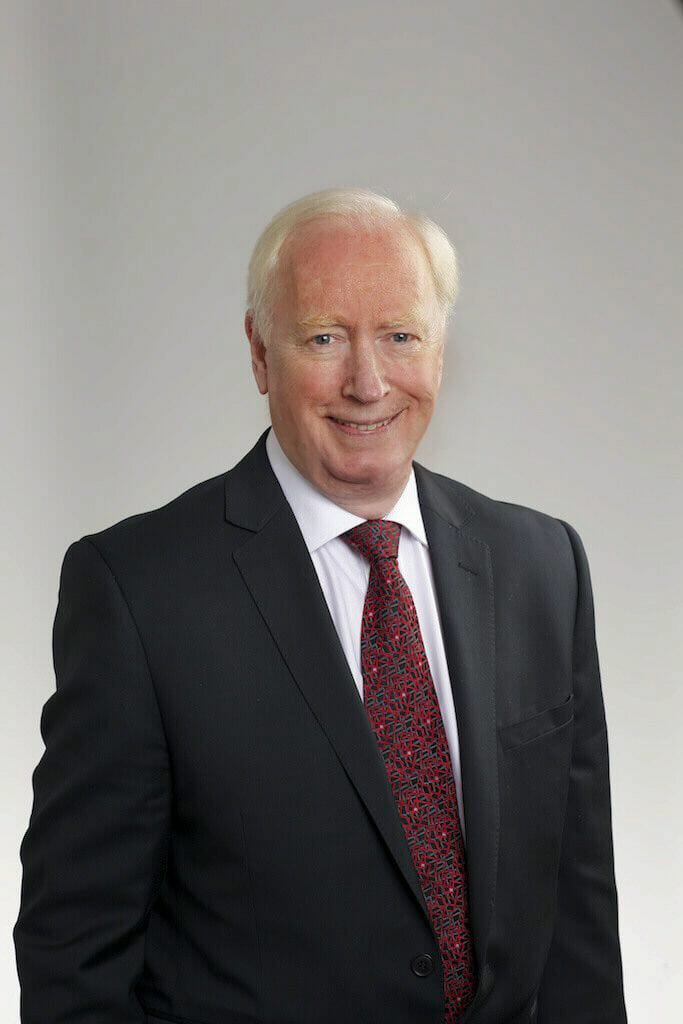 John M. Neill in dark suit and patterned tie.