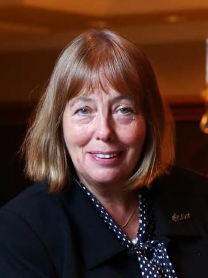 Julia Cleverdon in dark jacket and polka dot blouse smiles at the camera