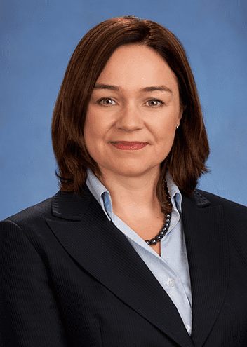 Lisa Donnelly in a navy suit and blue shirt, looks at the camera