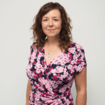 Louise Hunter in a floral printed dress, smiling at the camera