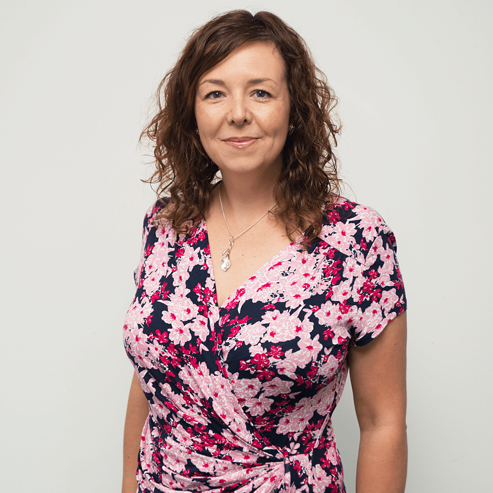 Louise Hunter in a floral printed dress, smiling at the camera